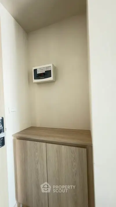 Compact storage area with wooden cabinet and electrical panel in modern apartment.