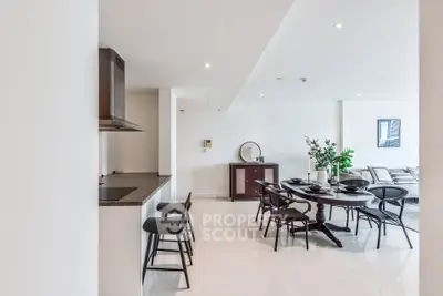 Spacious open-plan dining and living area with modern decor and sleek kitchen.