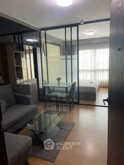 Modern apartment with open living and bedroom area, glass partition, and stylish furnishings.