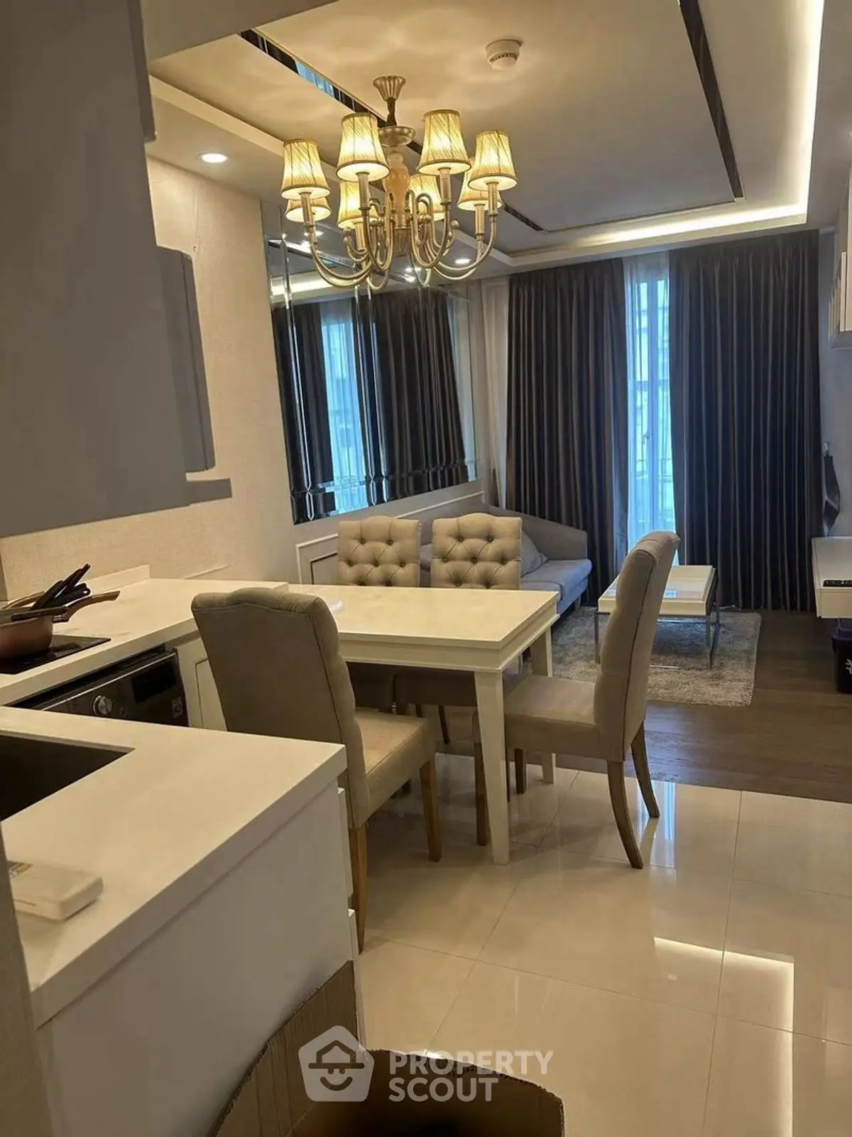 Elegant living room with dining area, featuring modern chandelier and cozy seating.