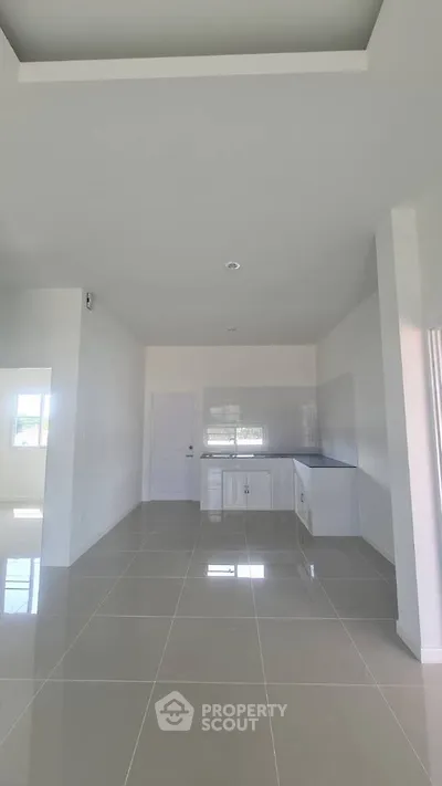 Spacious modern kitchen with sleek tile flooring and ample natural light.