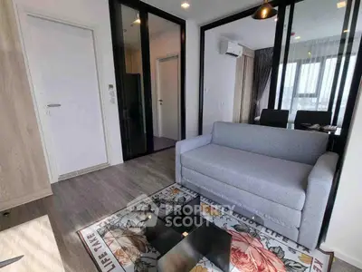 Modern living room with sleek design, featuring a cozy gray sofa and glass partition, perfect for urban living.