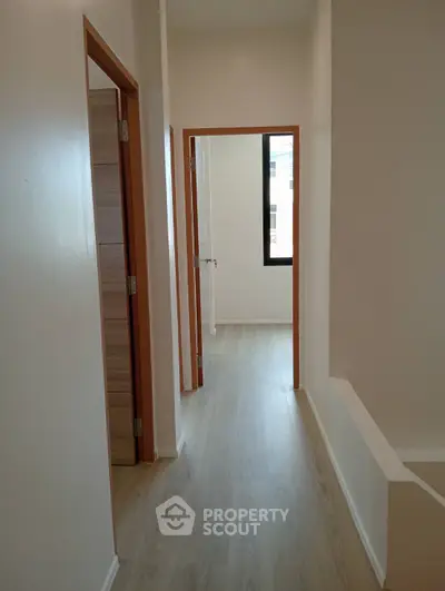 Bright hallway with wooden flooring and modern doors in a contemporary home.