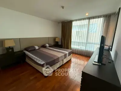 Spacious bedroom with modern decor and large window for natural light.