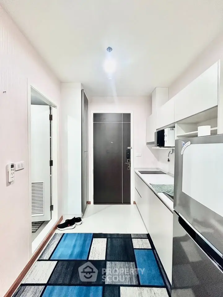 Modern kitchen with sleek white cabinets and stainless steel appliances in a compact layout.