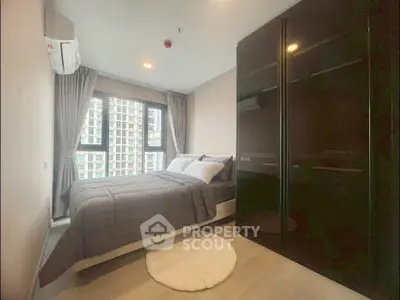 Modern bedroom with large window and sleek wardrobe in urban apartment.