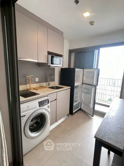 Modern kitchen with washing machine and open balcony view