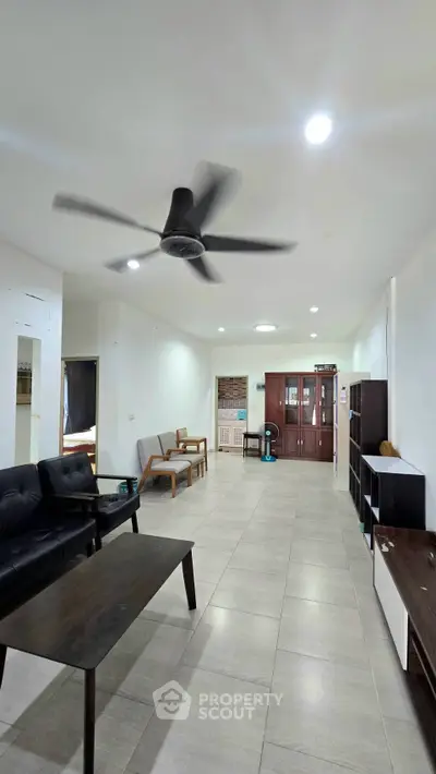 Spacious living room with modern furniture and ceiling fan, ideal for family gatherings.