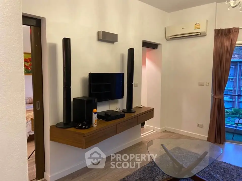 Modern living room with sleek entertainment setup and air conditioning, featuring a glimpse of a cozy bedroom.