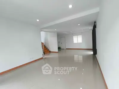 Spacious open-plan living room with glossy tiled floors and staircase, perfect for modern living.