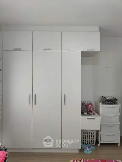 Spacious white wardrobe with ample storage in modern bedroom setting.