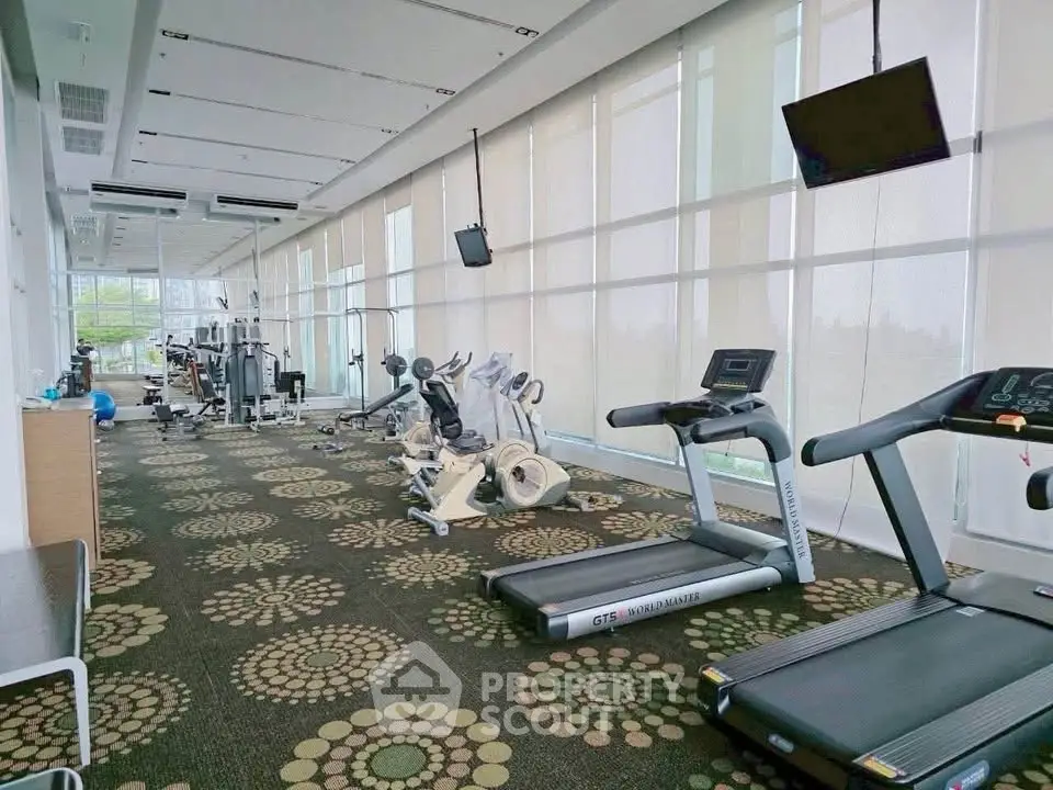 Spacious modern gym with state-of-the-art equipment and large windows for natural light.