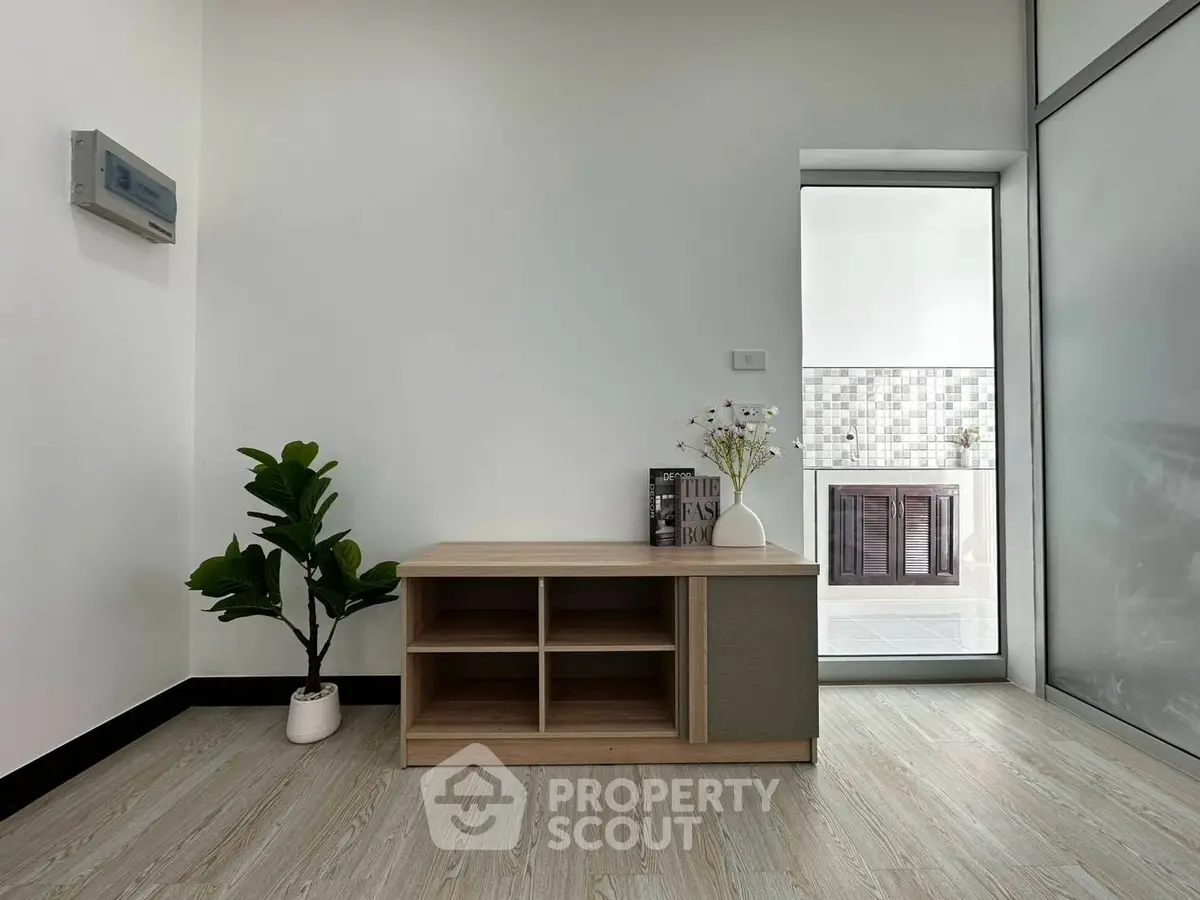 Modern minimalist interior with sleek wooden cabinet and potted plant, showcasing elegant flooring and natural light.