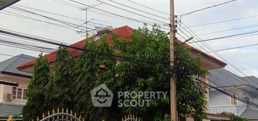 Charming suburban house with red roof and lush greenery, perfect for family living.