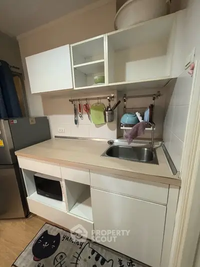 Modern compact kitchen with open shelving and sleek design in a cozy apartment.