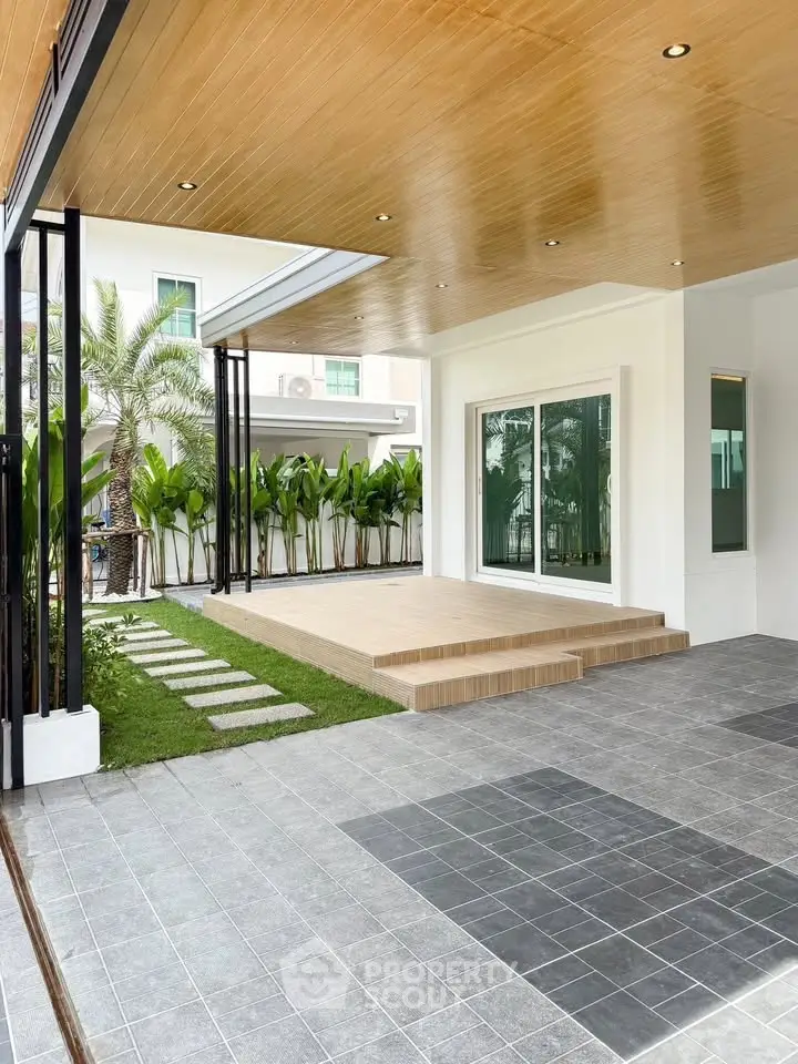 Modern home exterior with covered patio and lush garden, featuring sleek design and spacious outdoor area.