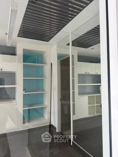 Modern office space with glass partitions and built-in shelving, ideal for professional work environment.