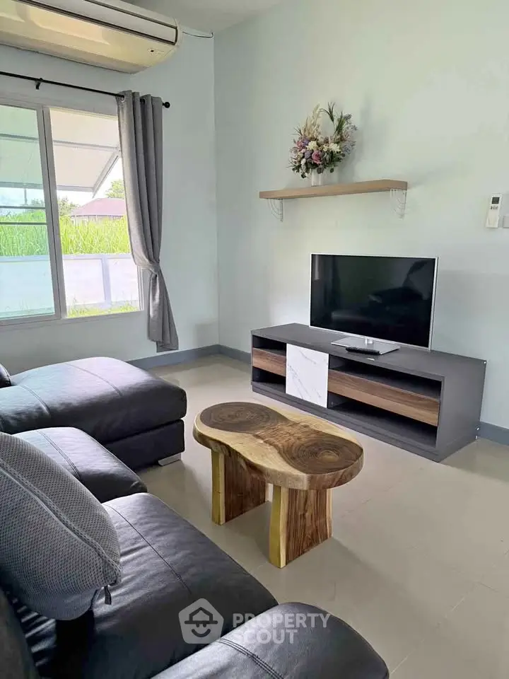 Charming living room with modern decor, featuring a cozy sofa, stylish TV stand, and a unique wooden coffee table.