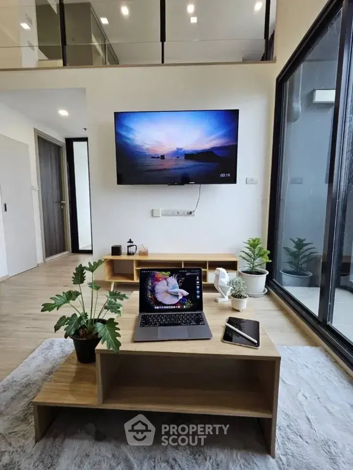 Modern living room with sleek design, large TV, and natural light from floor-to-ceiling windows.