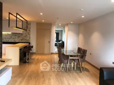 Spacious modern living room with open kitchen and dining area, featuring stylish furniture and elegant lighting.