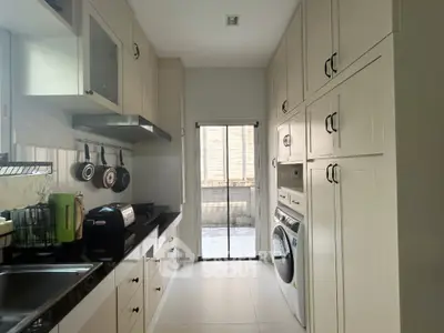 Sleek modern kitchen with built-in appliances and ample storage space, leading to a sunlit balcony perfect for urban living.