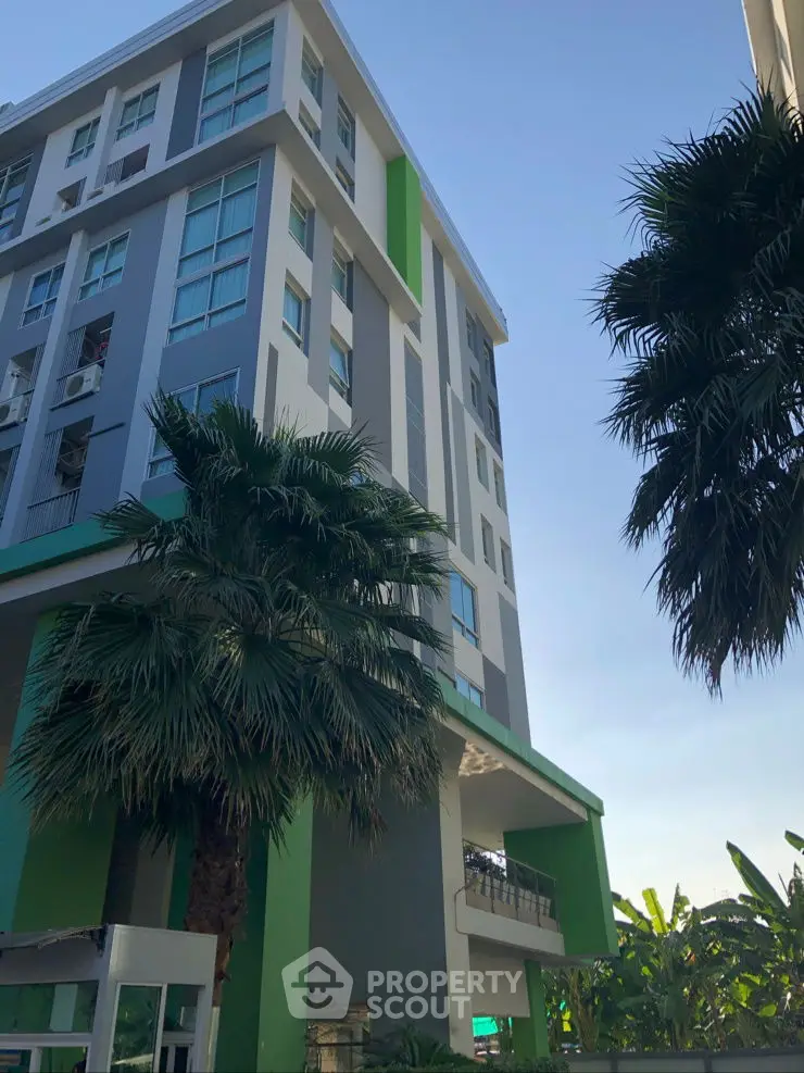 Modern apartment building with lush palm trees and clear blue sky