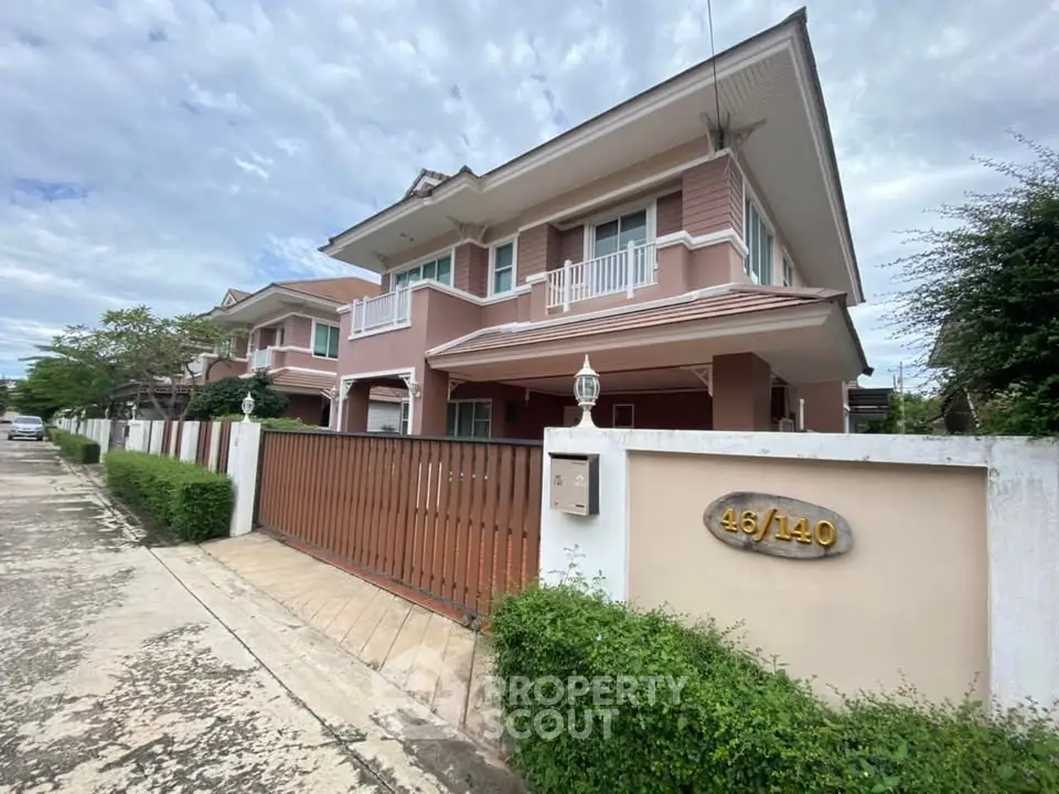 Charming two-story house with gated entrance and lush greenery in a serene neighborhood.