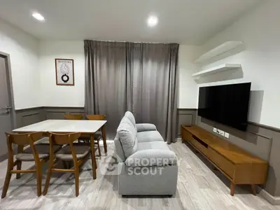 Modern living room with stylish furniture and dining area, featuring a sleek TV setup and elegant decor.