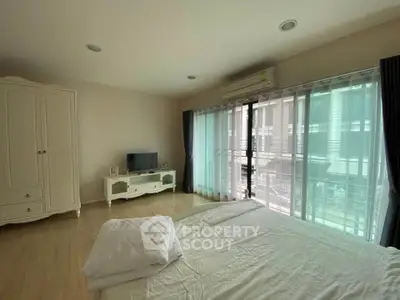 Spacious bedroom with natural light and modern furnishings in a stylish apartment.