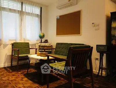 Charming vintage living room with parquet flooring and cozy seating area.