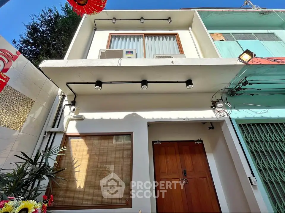 Charming two-story townhouse with modern facade and wooden door, perfect for urban living.