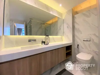 Modern bathroom with sleek marble finishes, large mirror, and undermount sink, perfect for a luxurious urban living experience.