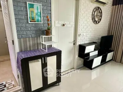 Modern living room with stylish decor and sleek furniture, featuring a wall clock and air conditioning.