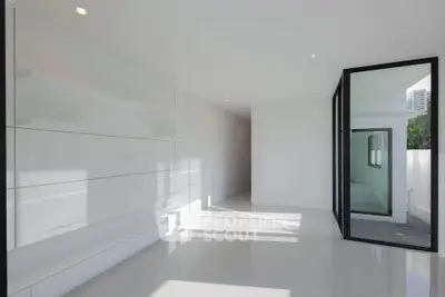 Modern minimalist interior with sleek white walls and large glass door, perfect for contemporary living.