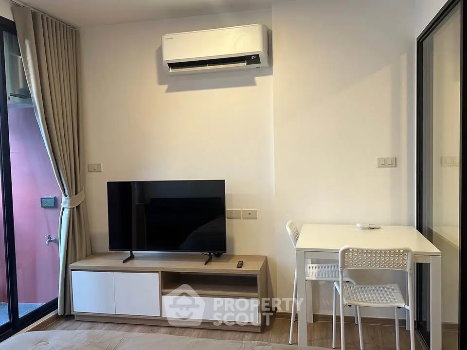 Modern living room with air conditioning, TV, and dining area in a stylish apartment.