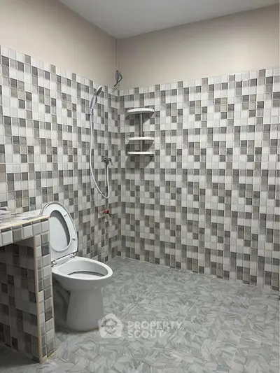 Spacious bathroom with modern tiled design and shower area.