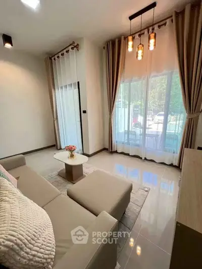 Elegant living room with cozy sofa and large windows offering natural light and garden view.