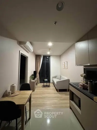 Modern living room with cozy seating and stylish decor in a compact apartment.