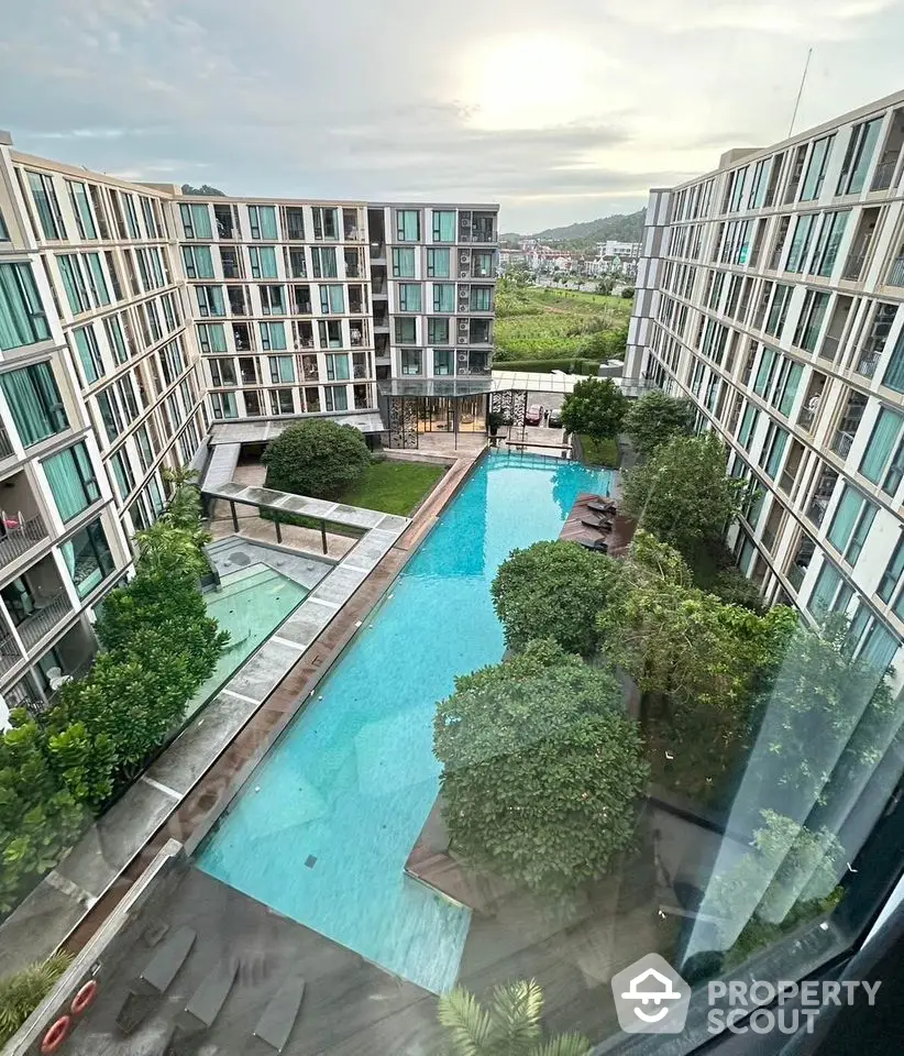 Stunning aerial view of modern apartment complex with central swimming pool and lush greenery.