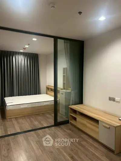 Modern bedroom with glass partition and wooden flooring in a stylish apartment.