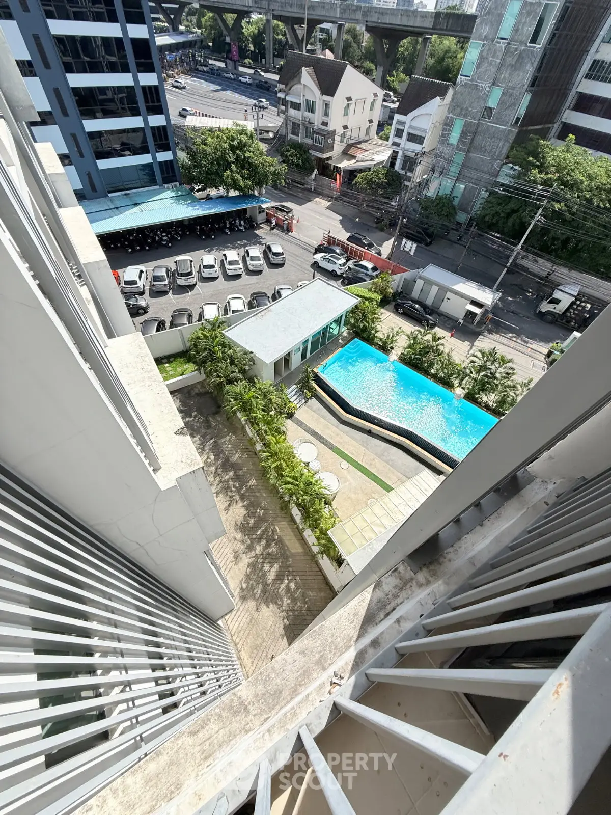 Stunning aerial view of modern apartment complex with pool and cityscape, perfect for urban living.