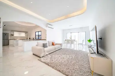 Spacious modern living room with open kitchen and dining area, featuring sleek design and natural light.