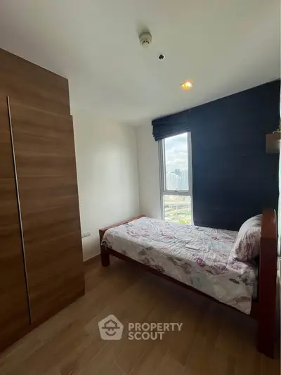 Cozy bedroom with wooden wardrobe and city view from window