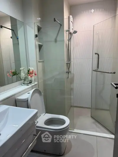 Modern bathroom with glass shower and sleek fixtures in contemporary apartment.