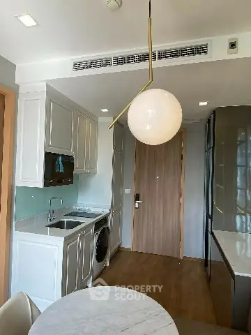 Modern kitchen with sleek cabinetry, integrated appliances, and stylish lighting in a compact layout.