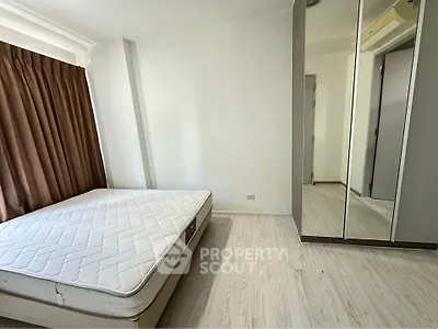 Spacious bedroom with large window and mirrored wardrobe in modern apartment.