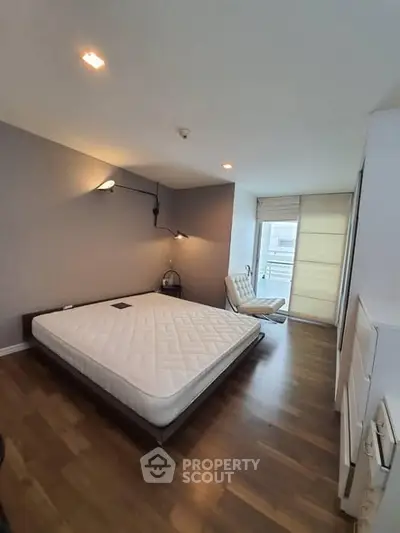 Spacious bedroom with modern decor and large window for natural light.