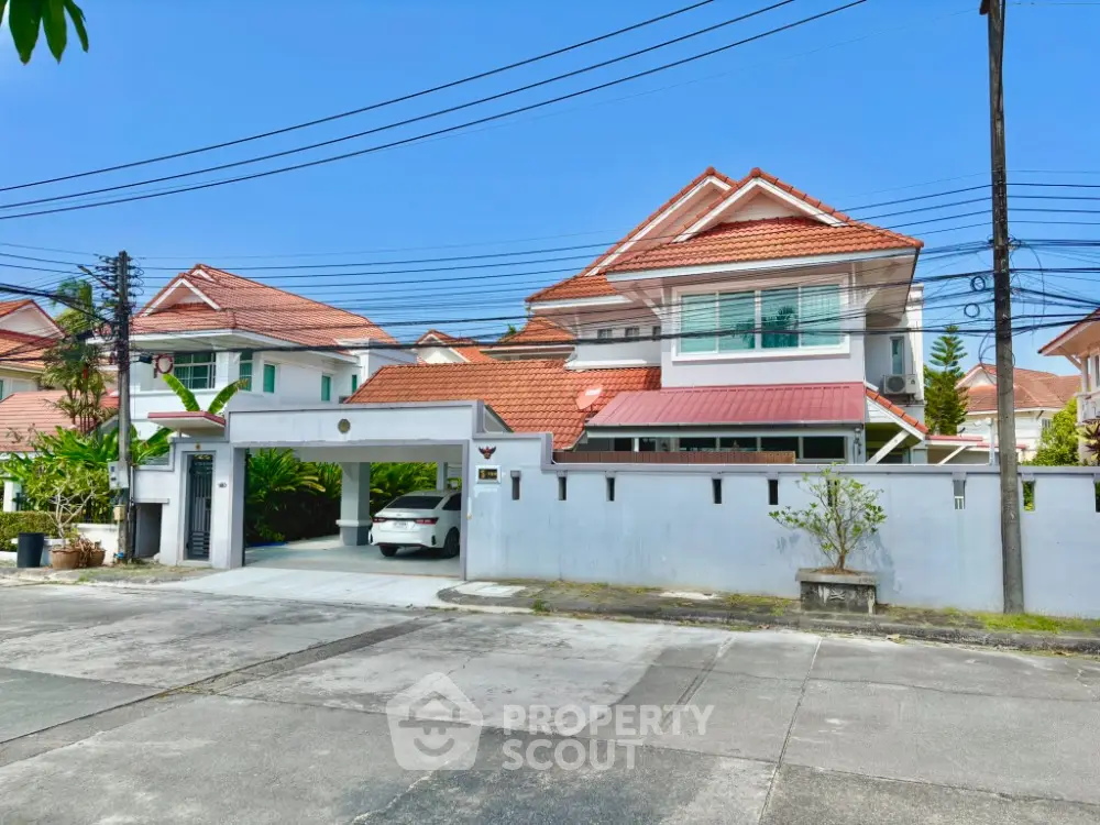 Charming suburban house with red roof and spacious driveway in a peaceful neighborhood.