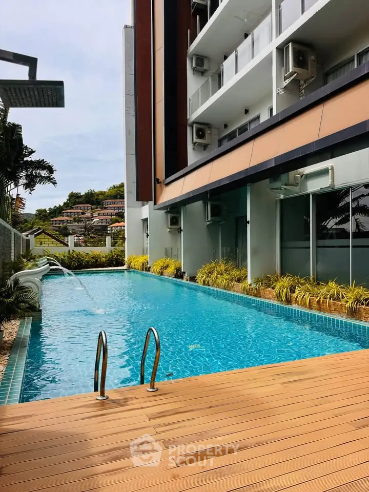 Modern apartment building with a luxurious outdoor pool and wooden deck, perfect for relaxation and leisure.