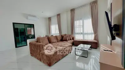 Spacious living room with modern brown sofa and large windows, perfect for relaxation.